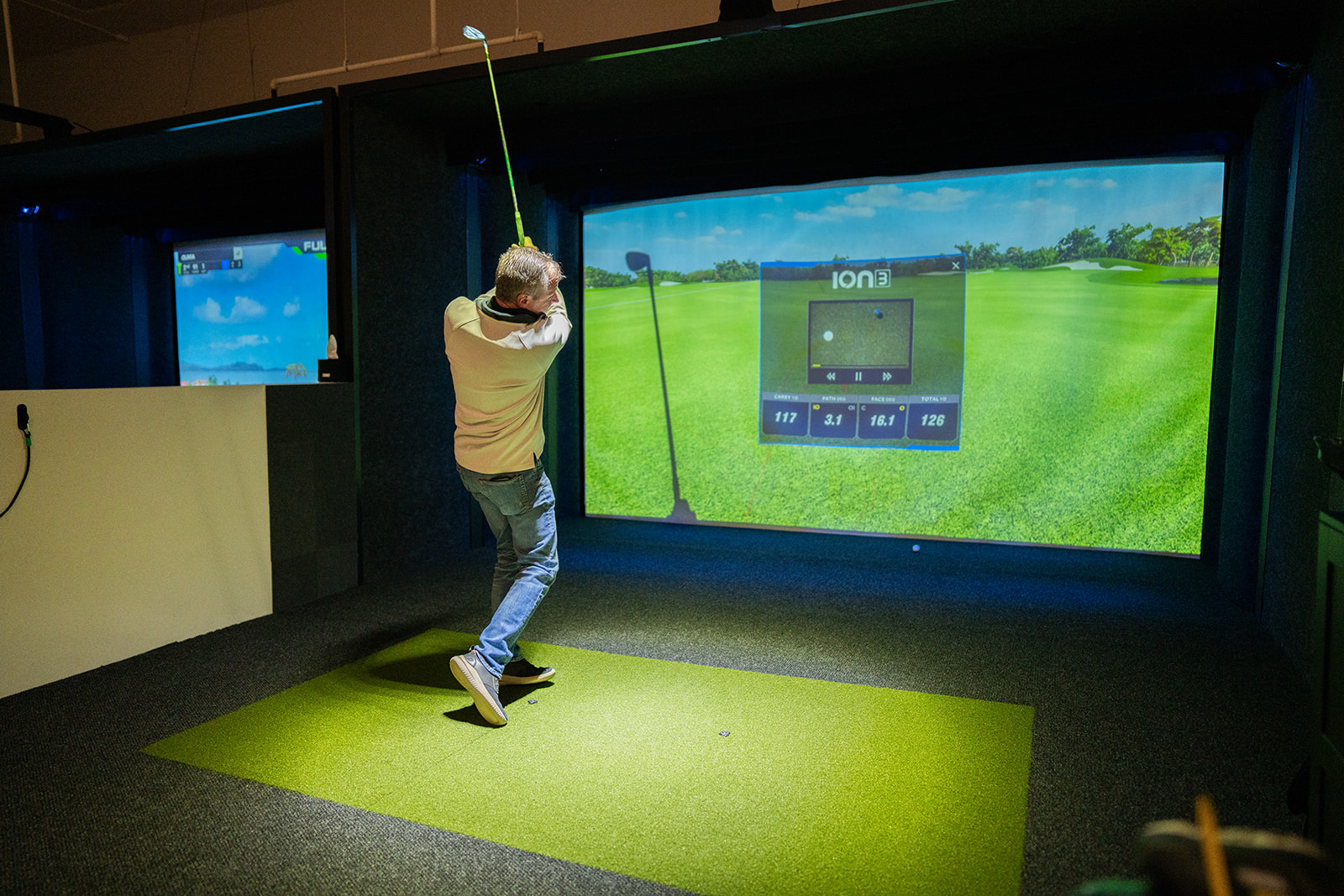 Golfer following through in a simulator bay